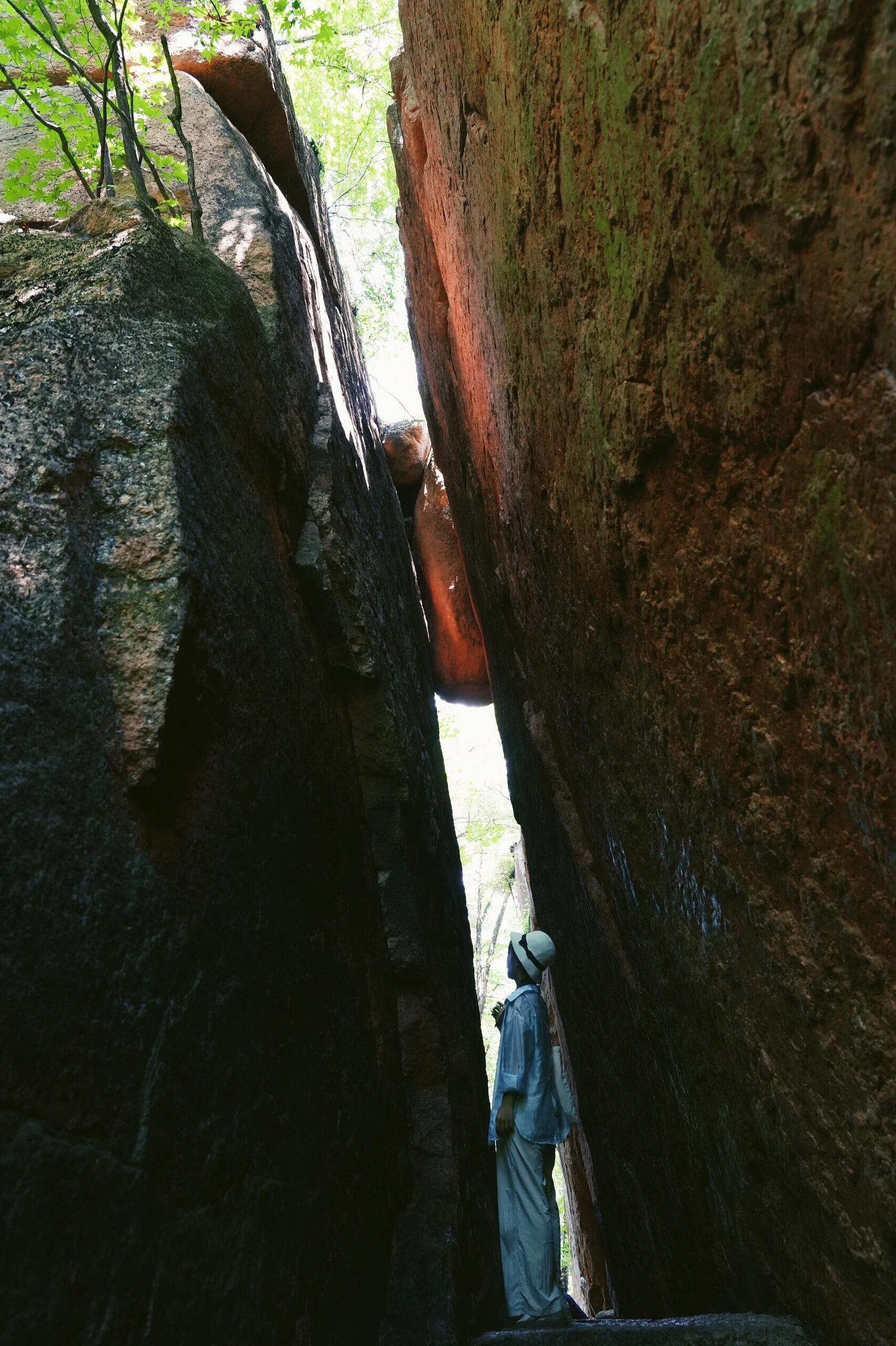 A person navigating a narrow, snow-dusted rock gorge, an adventurous winter scene in China.