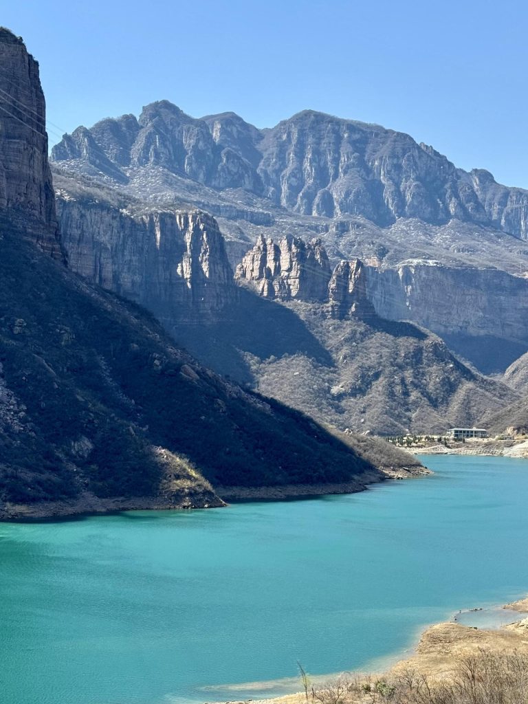 A majestic blue lake surrounded by towering mountains, a highlight of the Shanxi Taihang Exploration.