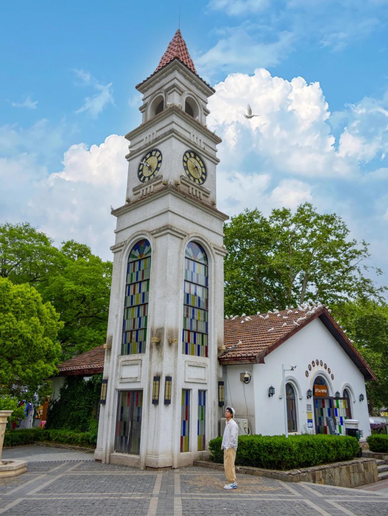 A white clock tower with a red roof against a blue sky, an architectural gem in Eastern China Exploration.