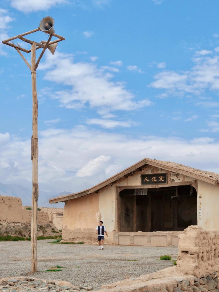 A local boy walks past an old building in Yongtai Ancient City, blending modern life with ancient history on this Hexi Corridor Adventure.