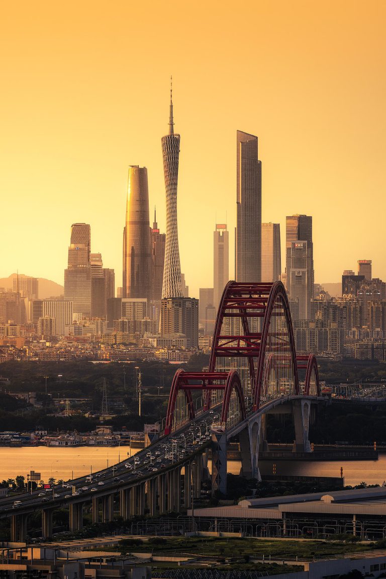 Sunset over Guangzhou CBD with Guangzhou Tower and a red bridge, showcasing the city's vibrant energy.