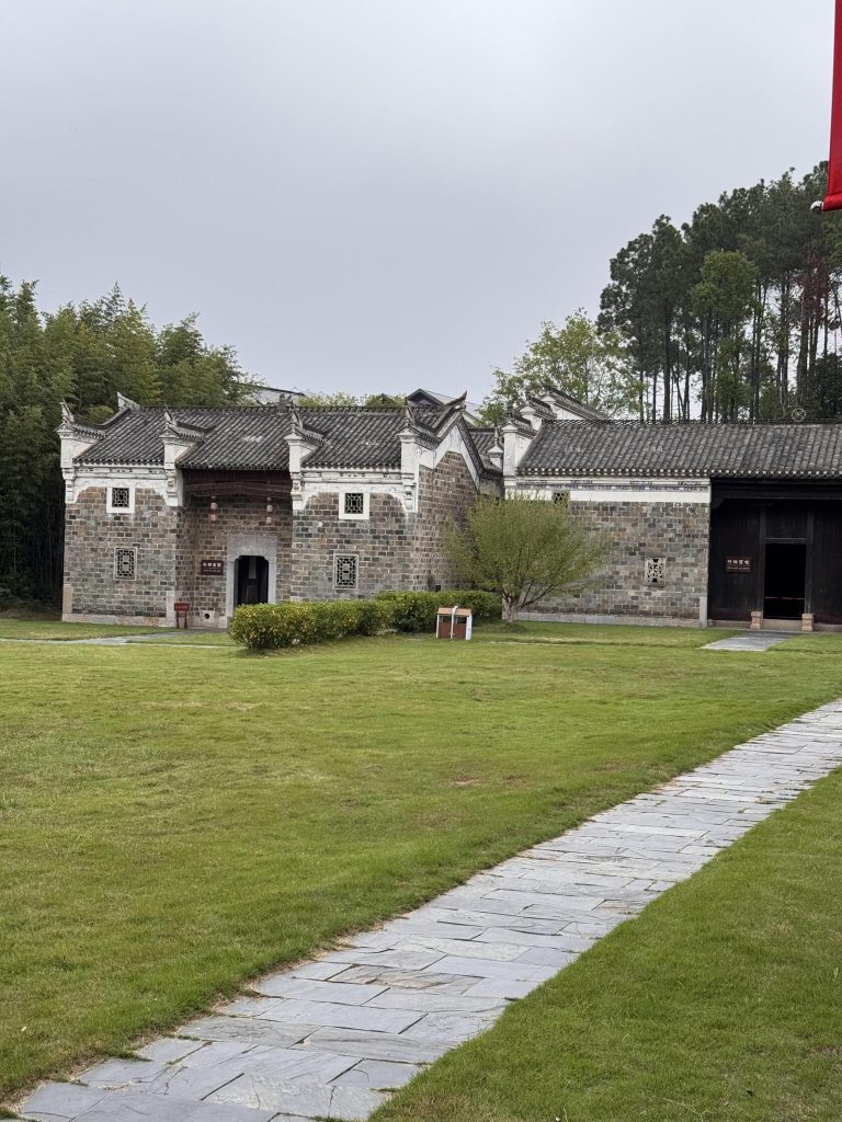 A traditional Chinese temple building with a grey tiled roof and red walls.